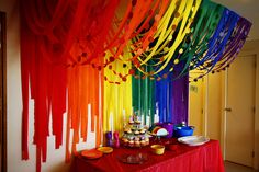 an image of a rainbow party with streamers on the ceiling and food in bowls