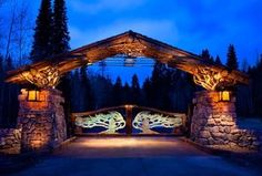 a lit up stone and wood gate with trees on it at night in the background