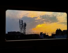 the sun is setting behind some power lines and buildings as seen from inside a train window