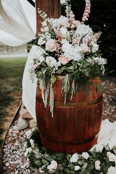 a wooden barrel filled with flowers and greenery