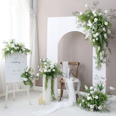 the wedding arch is decorated with white flowers and greenery, along with other floral arrangements