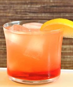 a close up of a drink in a glass with a slice of lemon on the rim