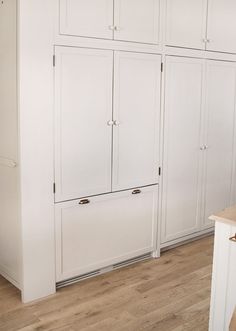 a kitchen with white cabinets and wood flooring on the side walk in closets