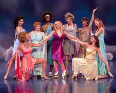 a group of women standing on top of a stage holding each other's hands