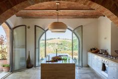 a kitchen with an arched doorway leading to the outside area and a large window on one side