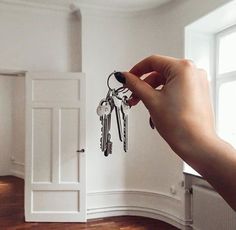 a hand holding keys in front of an open door