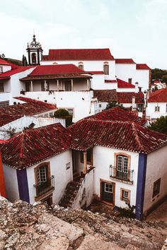 an old spanish style house with red tile roofing and white walls, surrounded by rocky terrain