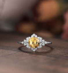 a yellow and white diamond ring sitting on top of a wooden table