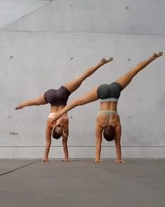 two women doing handstands in front of a wall