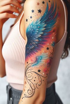 Channel your inner celestial being with this arm ink—angel wings and stars, a cosmic symphony. Colored Wing Tattoo, Angel Tattoo For Women On Arm, Angel Tattoo Designs For Women Beautiful, Angel Wings On Arm, Bright Tattoos For Women Half Sleeves, Angel Wings On Back Of Arm, Rainbow Angel Wings Tattoo, Angel Wing Tattoo Designs, Colorful Angel Wings Tattoo