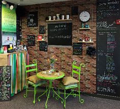 a small table and chairs in front of a chalkboard wall with writing on it