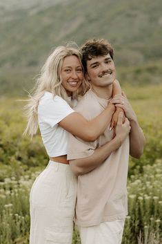 a man and woman hugging each other in the middle of a field