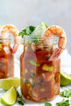 two mason jars filled with salsa and shrimp, garnished with cilantro