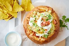 an open faced sandwich with sour cream and toppings next to tortilla chips