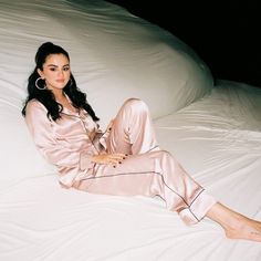 a woman sitting on top of a bed in pink pajamas and heels with her legs crossed