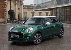 a green mini cooper parked in front of a building