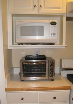 a microwave oven sitting on top of a counter next to a toaster oven in a kitchen