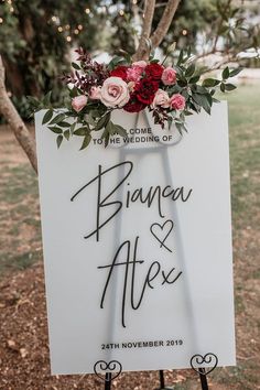 a sign with flowers and greenery on it that says, branoa & alex