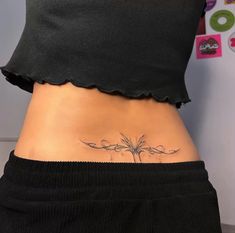 a woman's stomach with a flower tattoo on her lower back and the bottom part of her belly