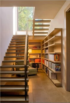 there is a staircase in the living room with bookshelves on both sides and a couch under it