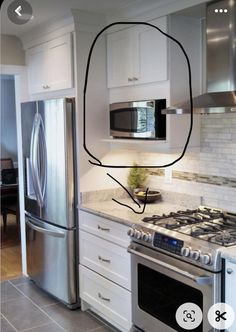 a kitchen with white cabinets and stainless steel appliances in the middle of the countertop