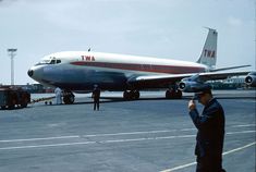 an airplane on the tarmac at an airport with people standing around and talking on their cell phones