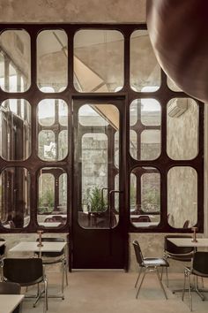 an empty classroom with tables and chairs in front of large glass windows that look out onto the courtyard