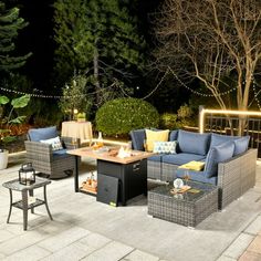 an outdoor patio with furniture and lights on the trees in the background, at night