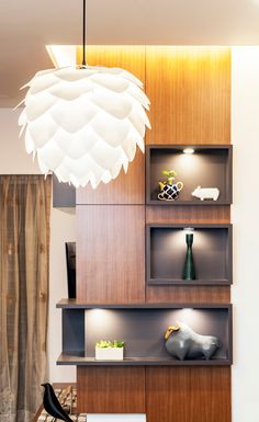 a living room filled with lots of furniture and lighting fixture hanging from the ceiling above it