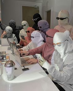 a group of people in costumes sitting at a table with laptops