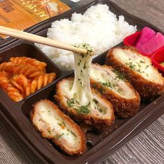 a bento box filled with rice, meat and veggies next to chopsticks