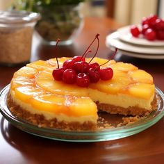 a pineapple upside down cheesecake with cherries on top sits on a table