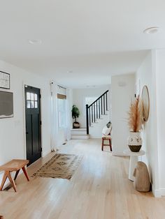 a living room with hard wood floors and white walls is seen in this image from the front door