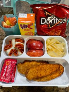 a lunch tray with fish, chips, apples, and other food items on it