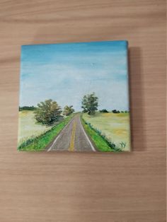 a painting of a country road on a wooden surface