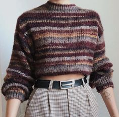 a close up of a woman wearing a sweater and skirt with her hands in her pockets