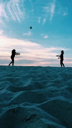 two people playing with a ball in the sand