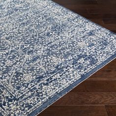 a blue and white area rug on top of a hard wood floor with dark wooden floors