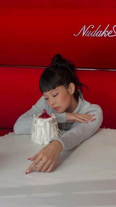 a woman laying on top of a table next to a cake