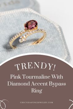 a pink tourmaline with diamond accent bypass ring on top of a blue box