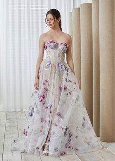 a woman in a strapless dress standing on a wooden floor with flowers all over it