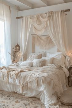 a white bed sitting in a bedroom next to a window with curtains on top of it