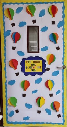 a door decorated with paper hot air balloons and the words fly high and touch the sky