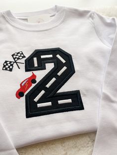 a white shirt with the number two on it and a red truck in front of it