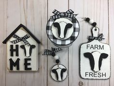 three farm signs hanging on the side of a white wooden wall next to a house