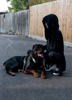 a person in a black hoodie sitting next to a dog