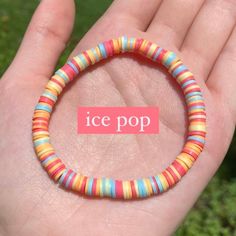 a hand holding an ice pop bracelet in it's palm with a pink sticker on it