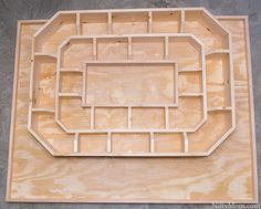 an unfinished wooden box with holes in the middle on top of it, sitting on a concrete floor