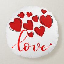 a round pillow with red hearts and the word love written on it in cursive font