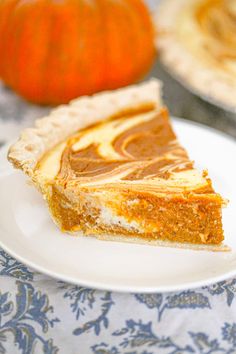 a slice of pumpkin pie on a white plate with a blue and white tablecloth